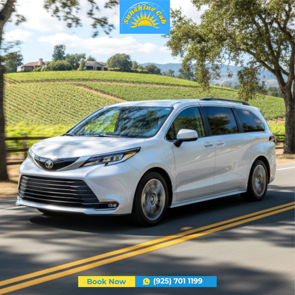 white Toyota Sienna hybrid minivan driving past lush green vineyards in the Northern California countryside, representing Sunshine Cab's professional transportation fleet.